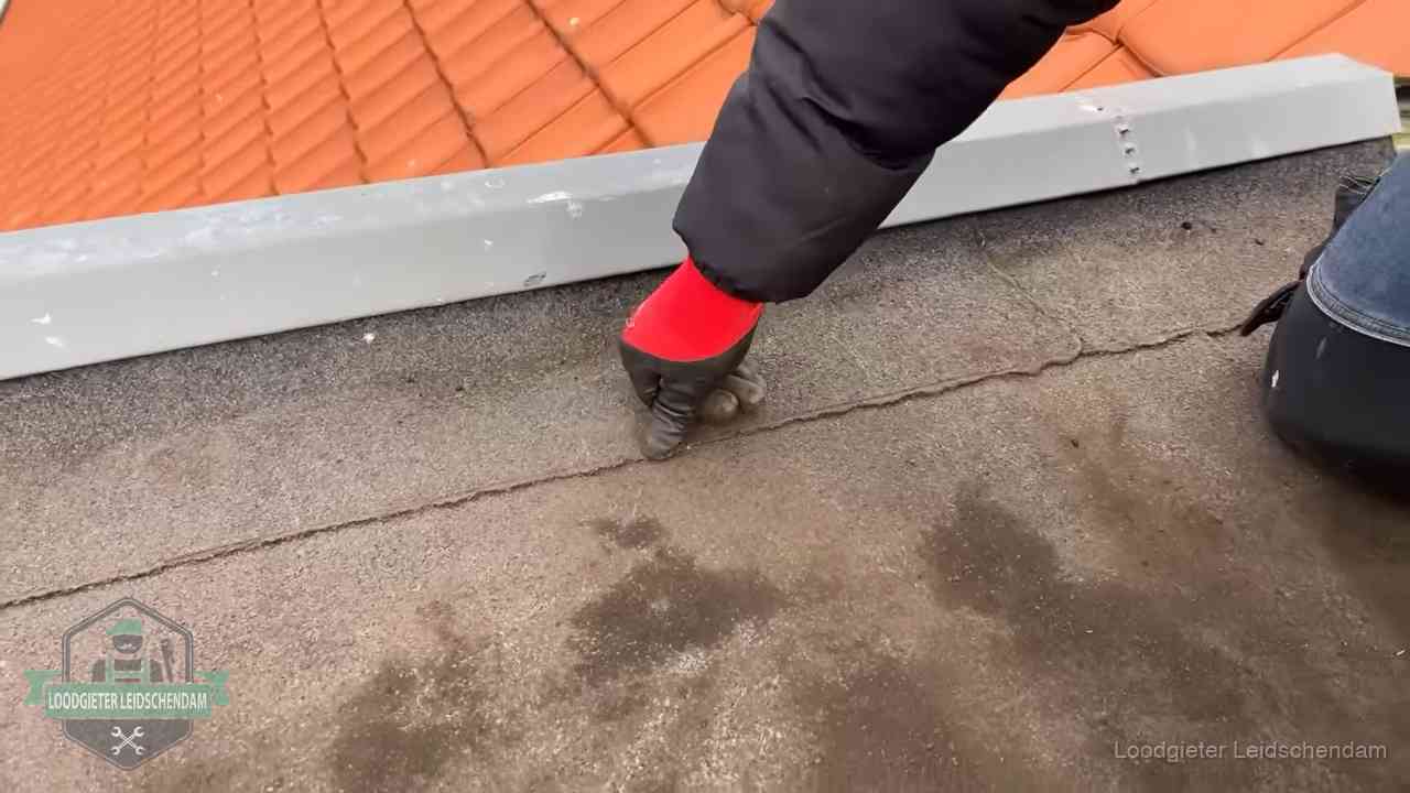 Lekkage bij de naad van een plat dak in Leidschendam Vakman wijst een naad met vochtplekken aan op een bitumen plat dak in Leidschendam