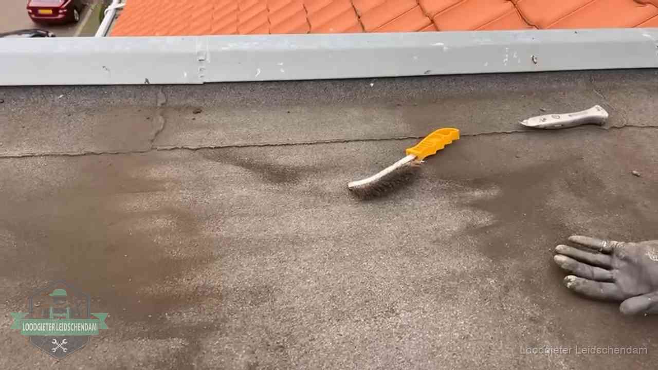 Kosten van daklekkage-reparatie in Leidschendam Dakdekker bereidt een bitumen plat dak voor op reparatie bij de daktrim in Leidschendam