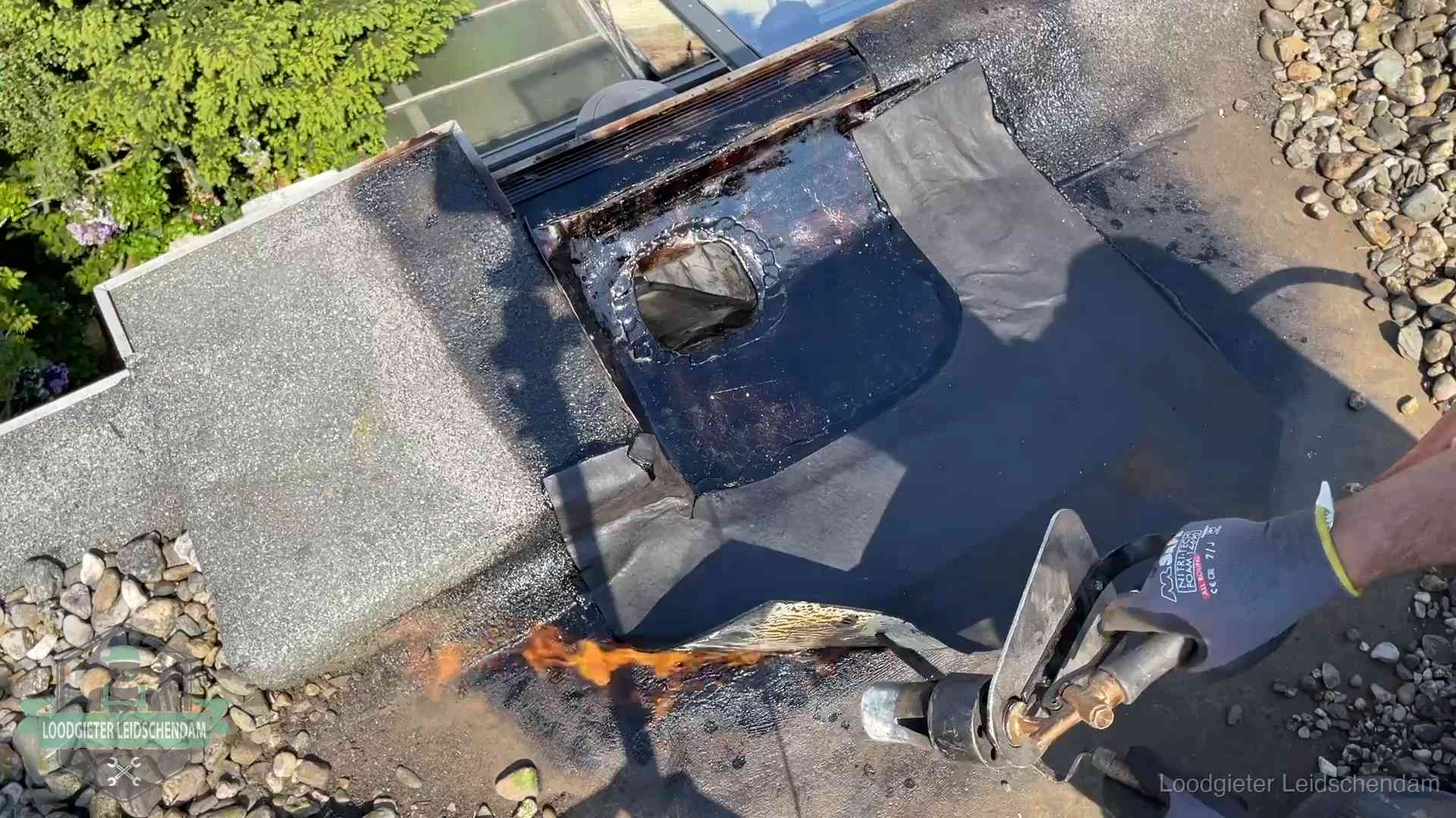 Daklekkage repareren in Leidschendam Dakdekker brandt bitumen rond een doorvoer tijdens een daklekkage-reparatie in Leidschendam