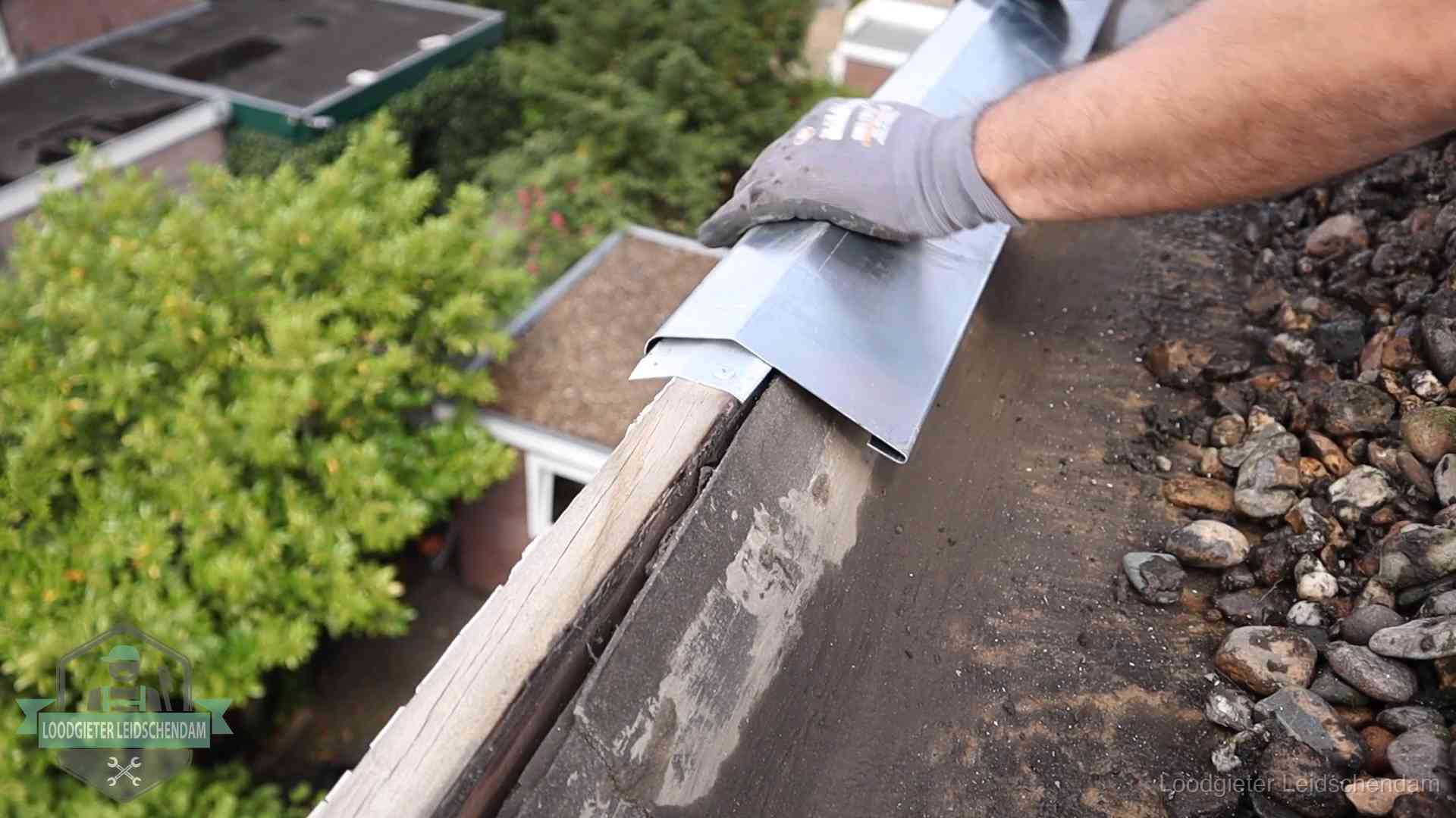 Daklekkage per wijk in Leidschendam Dakdekker plaatst een zinken deklijst op een dakrand met uitzicht over een woonwijk in Leidschendam