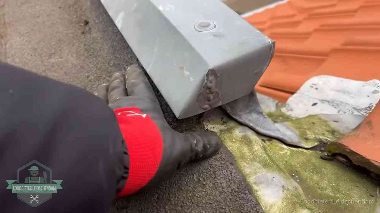 Hemelwaterafvoer en dakgoot controleren in Leidschendam Controle van een zinken hemelwaterafvoer met loodslab bij dakpannen in Leidschendam