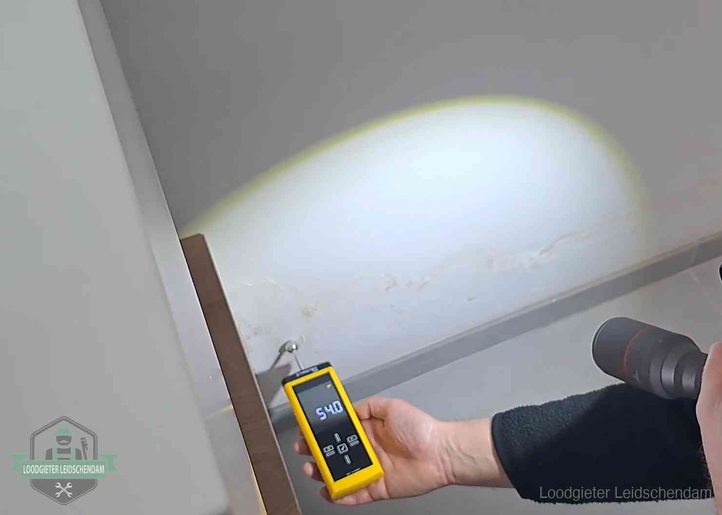 Vochtmeter tegen een natte wand met lekkagesporen in Leidschendam