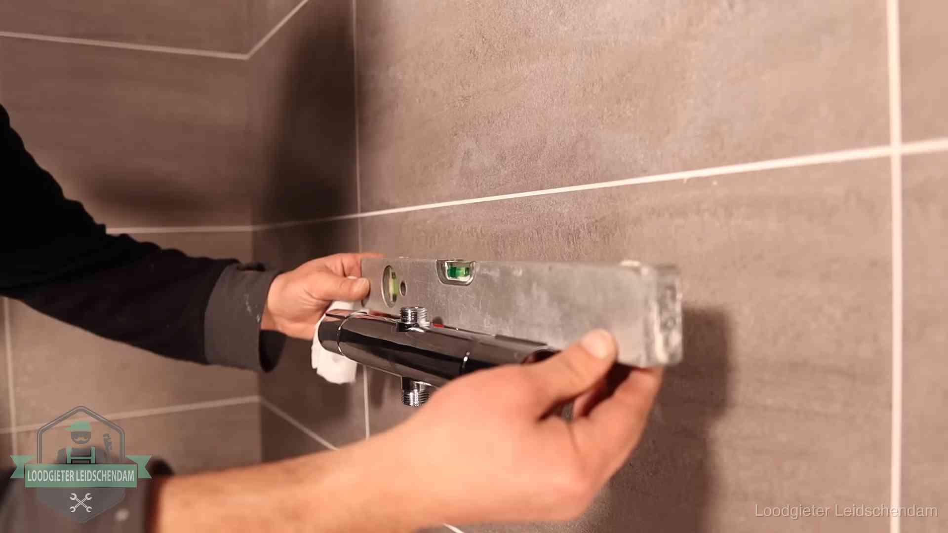Loodgietersbedrijf voor sanitair in Leidschendam Loodgieter lijnt een douchekraan uit met een waterpas in een woning in Leidschendam