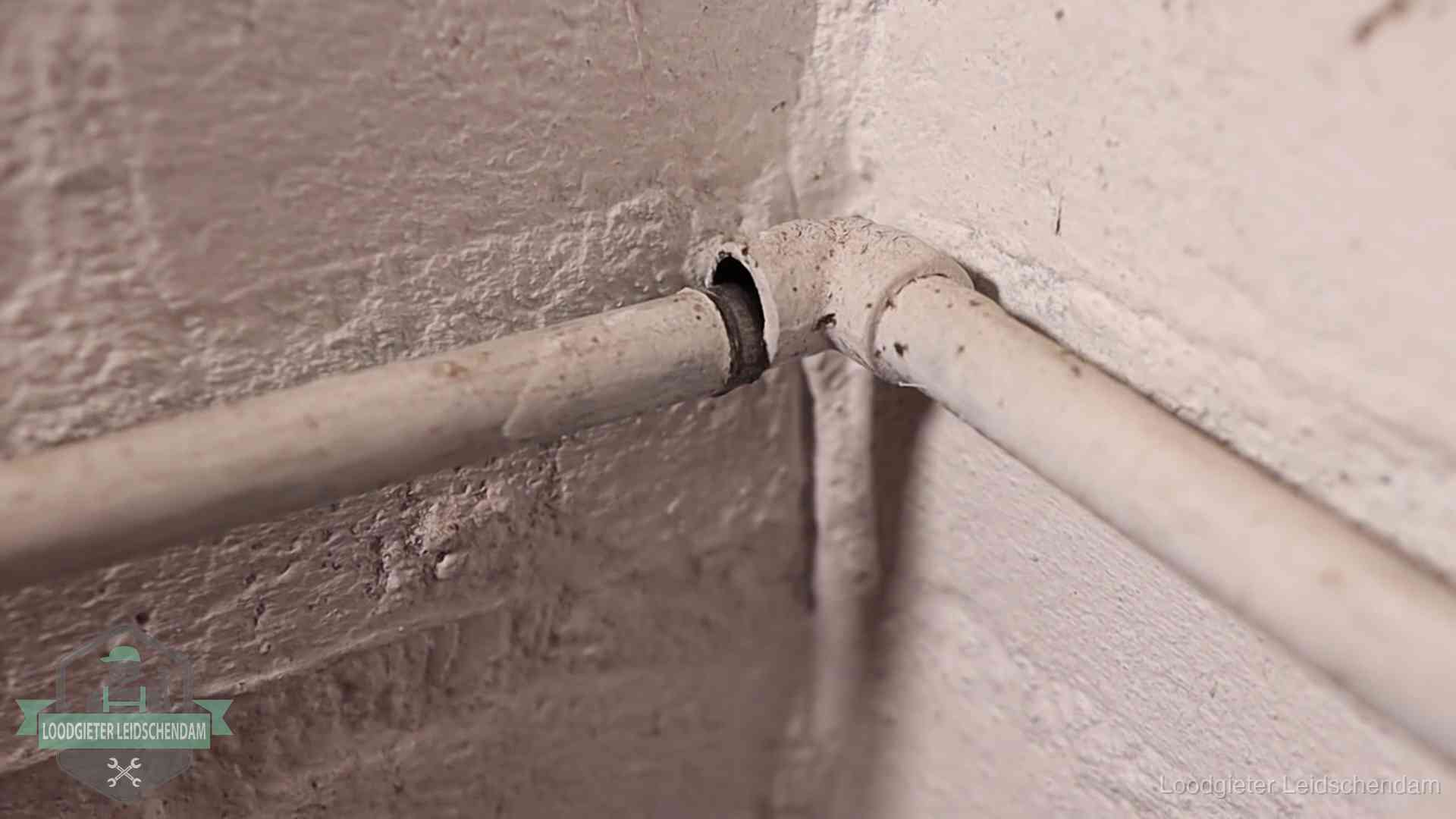 Oude geverfde waterleiding met een losliggende fitting in een woning in Leidschendam