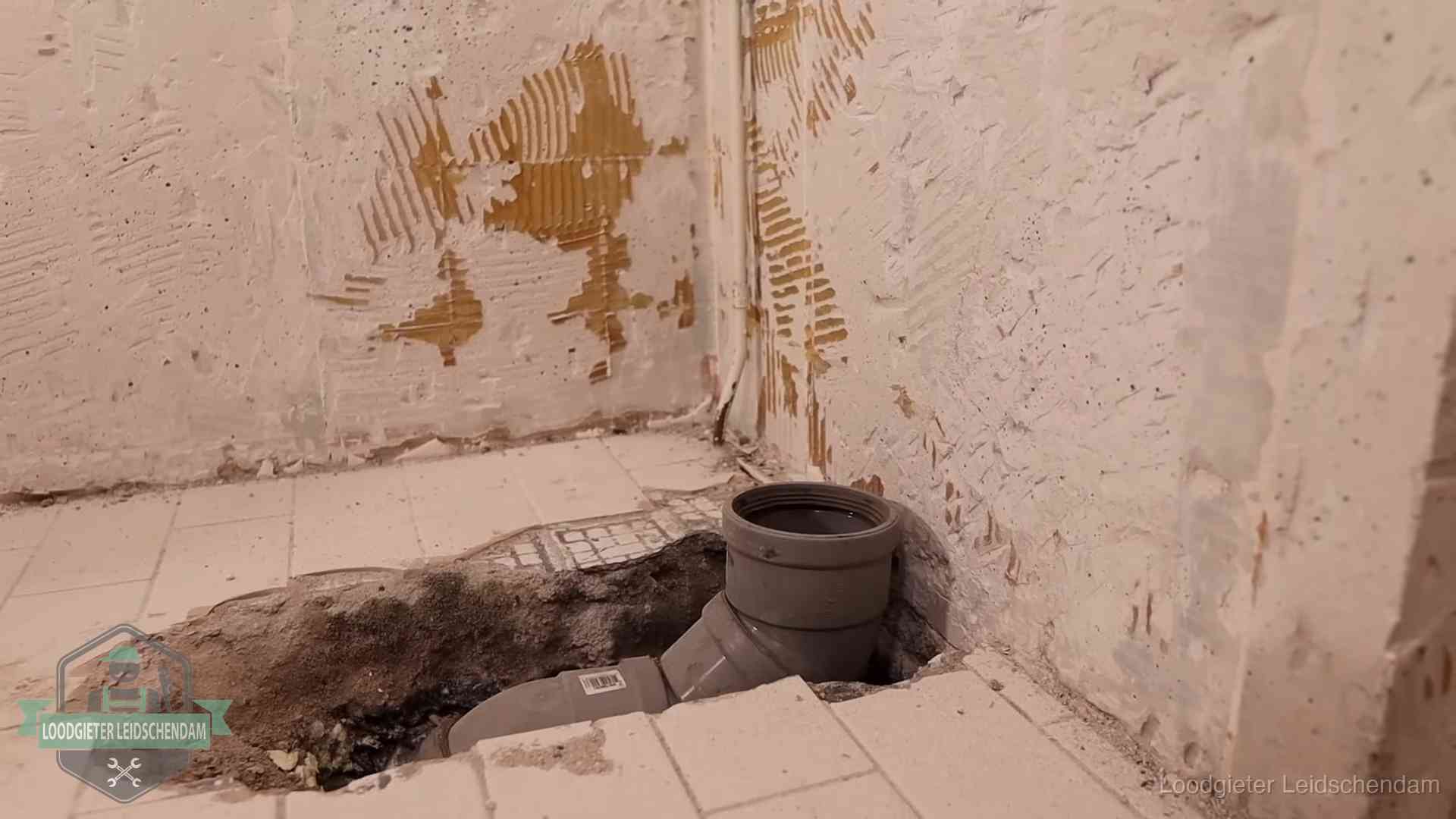 Verzakt riool herstellen in Leidschendam Opengebroken vloer met een nieuwe pvc-rioolbocht in een gegraven sleuf in Leidschendam