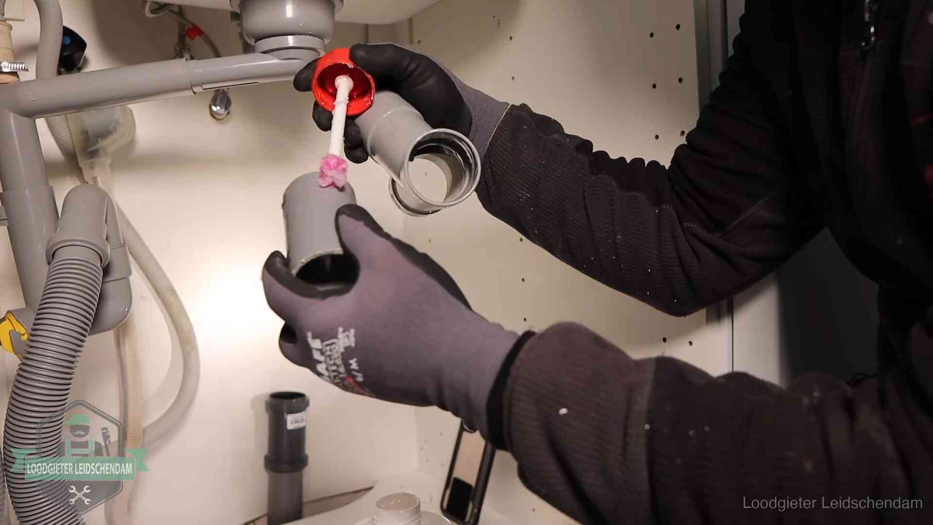 Oorzaak van een verstopte afvoer in Leidschendam Loodgieter demonteert en reinigt de sifon onder een keukenkast in Leidschendam