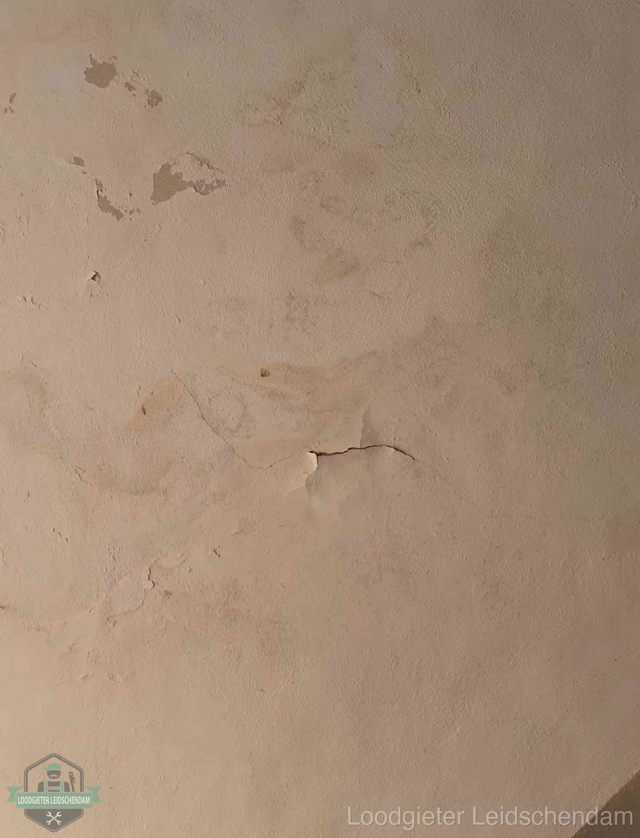 Vochtkringen en afbladderende verf op een plafond in Leidschendam, schade voor het meetrapport en de verzekering